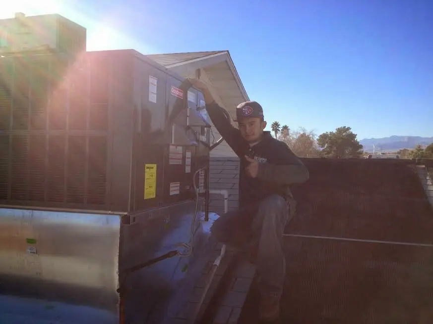 HVAC technician performing Heat Pump Repair on a rooftop unit in Maynard